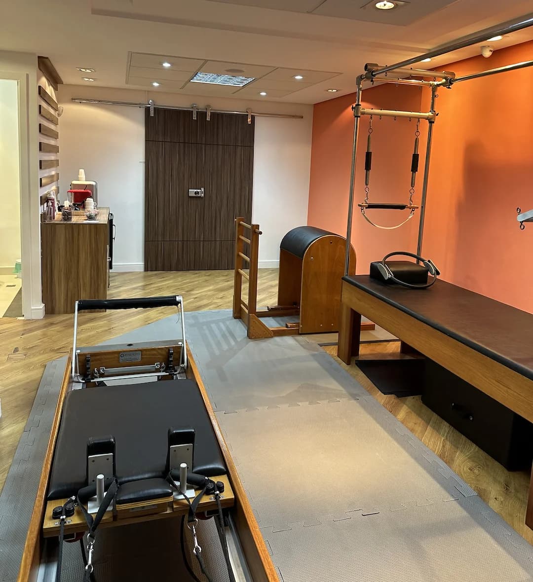 Sala de Pilates da Vyta, com parede coral, cadillac, barril e reformer sobre piso de madeira