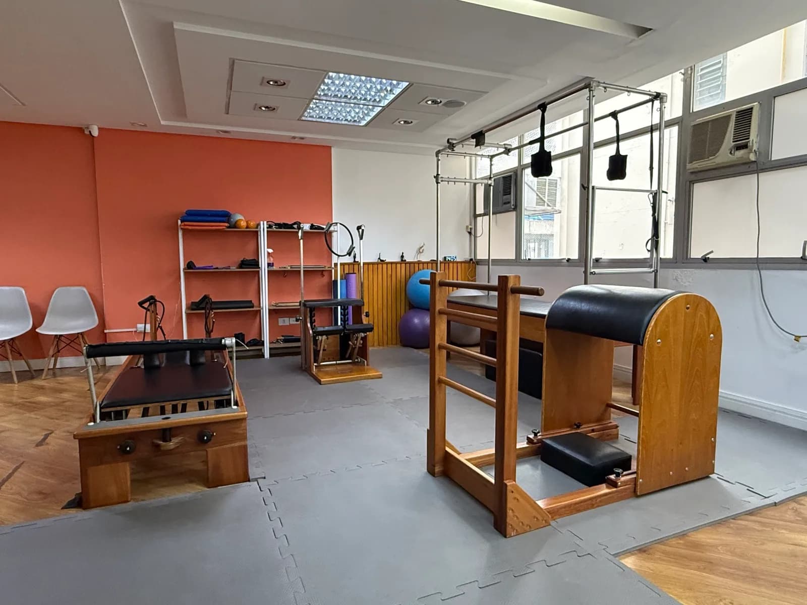 Fileira de aparelhos de Pilates da unidade Consolação da Vyta, com reformer, cadillac e escada sueca junto à parede coral